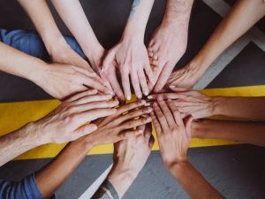 Diverse group of hands united in a circle, symbolizing the support network crucial for independent living with disability.