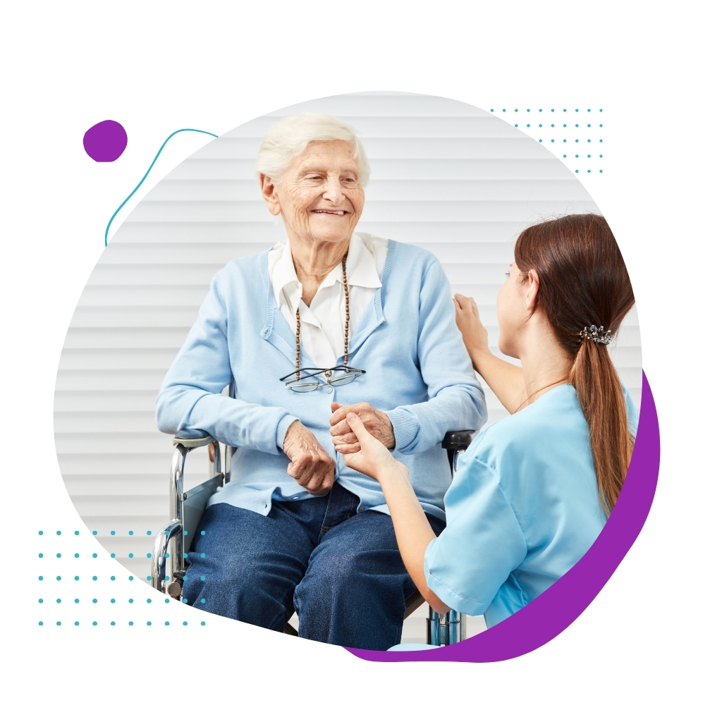 A woman engages in conversation with an elderly woman in a wheelchair, highlighting compassionate care in Disability Plan Services.