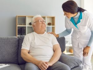 An occupational therapist assists an elderly man with daily tasks, demonstrating strategies for independent living to enhance his quality of life.